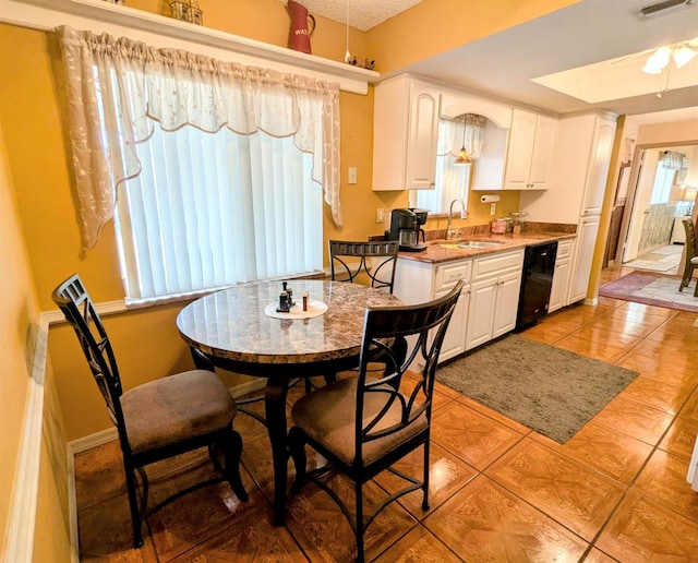 kitchen with sink, light tile patterned floors, and white cabinets