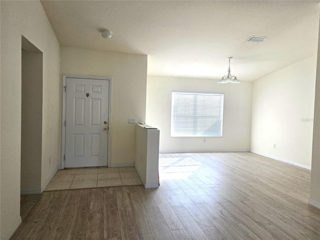 entryway with light wood-type flooring and a notable chandelier