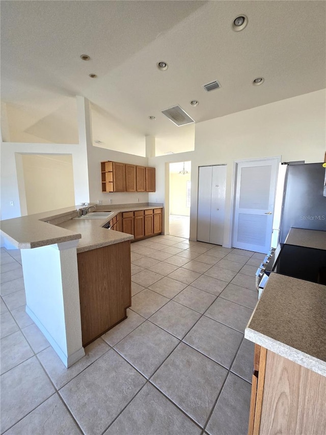 kitchen with sink, appliances with stainless steel finishes, light tile patterned floors, and kitchen peninsula