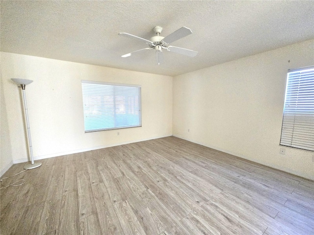 unfurnished room featuring light hardwood / wood-style floors, ceiling fan, a healthy amount of sunlight, and a textured ceiling