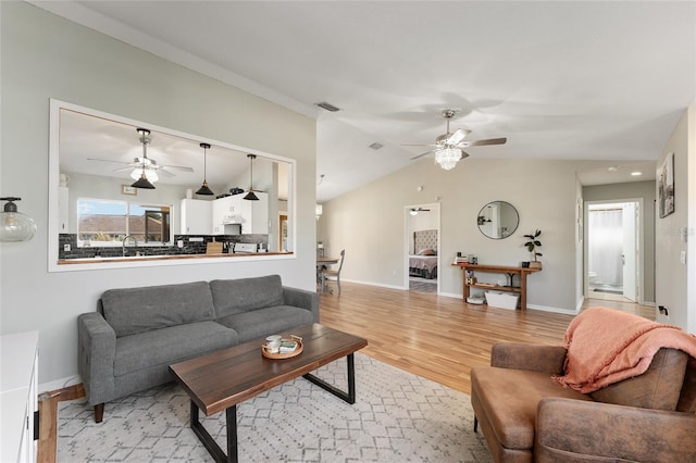 living room featuring ceiling fan, lofted ceiling, and light wood-type flooring