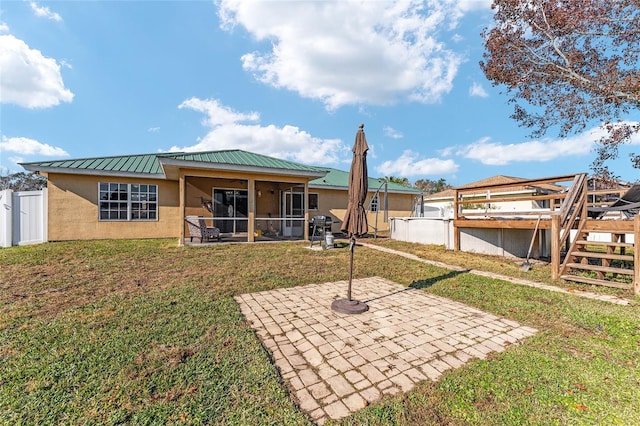 rear view of property featuring a sunroom, a yard, and a patio area