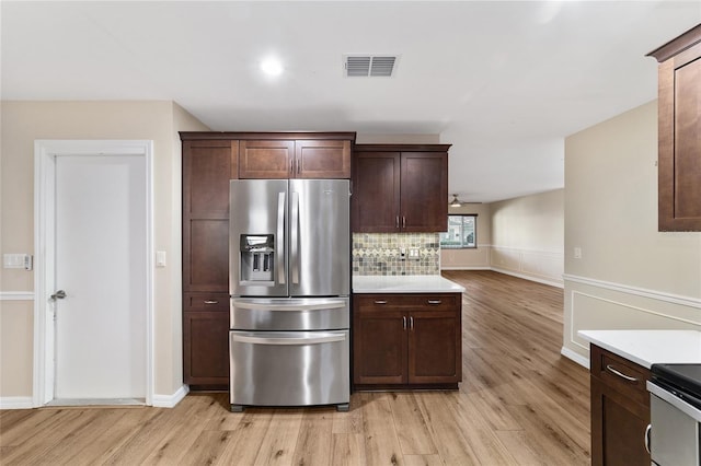 kitchen featuring dark brown cabinetry, appliances with stainless steel finishes, light hardwood / wood-style flooring, and tasteful backsplash