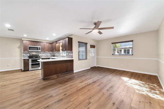 kitchen with kitchen peninsula, ceiling fan, stainless steel appliances, tasteful backsplash, and light wood-type flooring