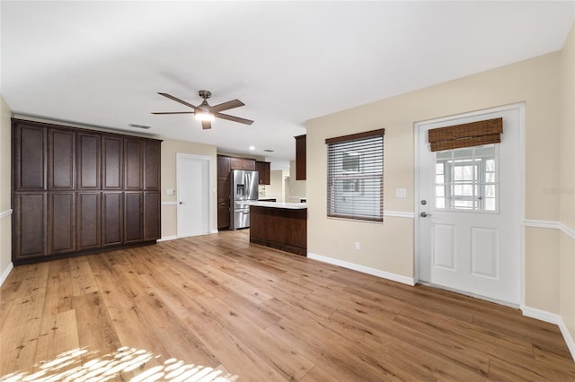 kitchen featuring ceiling fan, dark brown cabinetry, stainless steel fridge, and light wood-type flooring