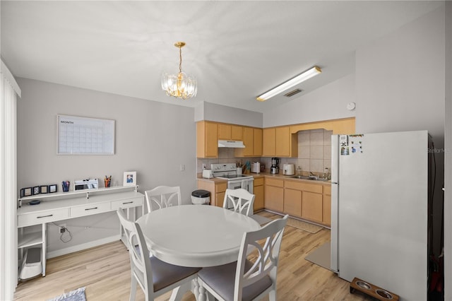 dining room with a notable chandelier, light wood-type flooring, and vaulted ceiling