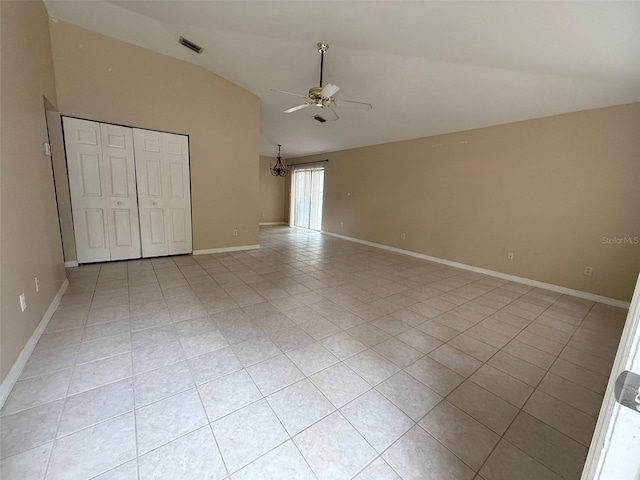 unfurnished bedroom with lofted ceiling, ceiling fan with notable chandelier, light tile patterned floors, and a closet