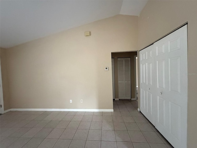 tiled spare room with vaulted ceiling