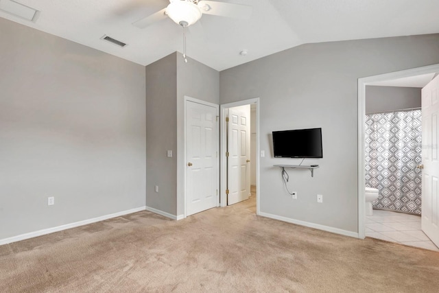 unfurnished bedroom featuring vaulted ceiling, ceiling fan, ensuite bathroom, and light colored carpet