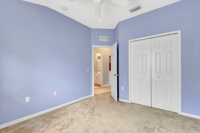 unfurnished bedroom with light carpet, ceiling fan, a closet, and vaulted ceiling