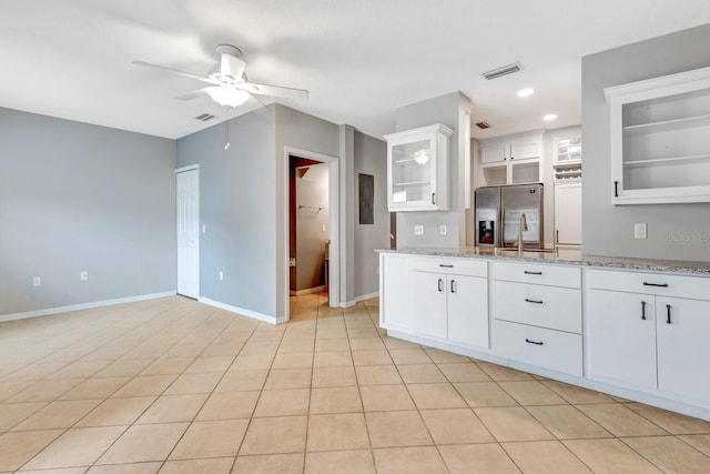 kitchen featuring light stone counters, light tile patterned floors, white cabinets, and stainless steel fridge with ice dispenser