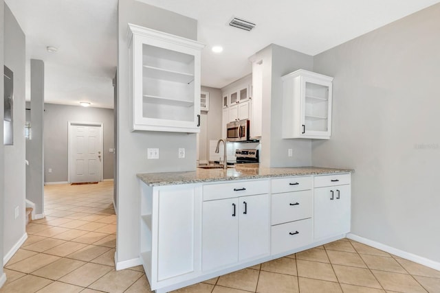 kitchen featuring light tile patterned floors, white cabinetry, sink, and light stone countertops