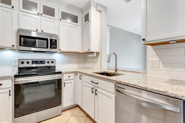 kitchen with tasteful backsplash, sink, light tile patterned flooring, stainless steel appliances, and white cabinets