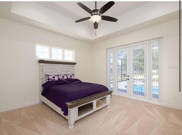 carpeted bedroom featuring ceiling fan, french doors, a raised ceiling, and access to exterior