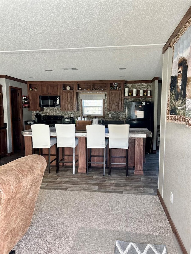 kitchen with a kitchen island, backsplash, a breakfast bar, and dark hardwood / wood-style flooring