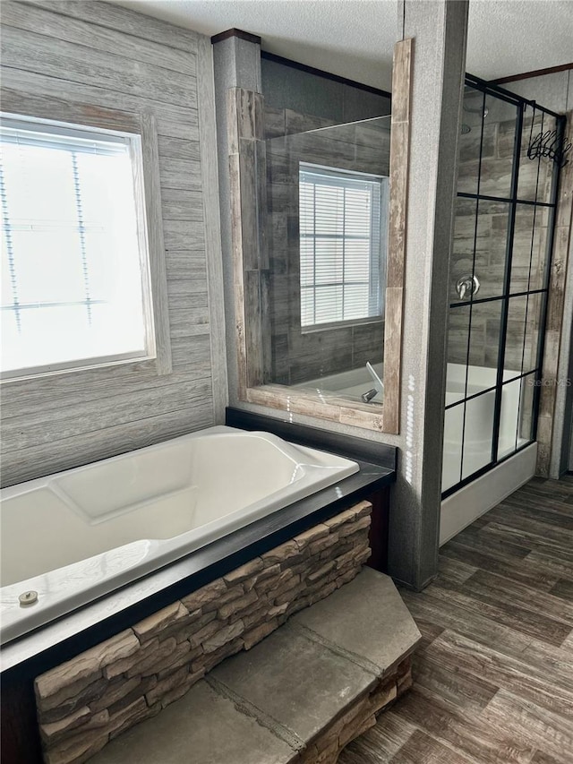 bathroom featuring a textured ceiling, wood-type flooring, and independent shower and bath