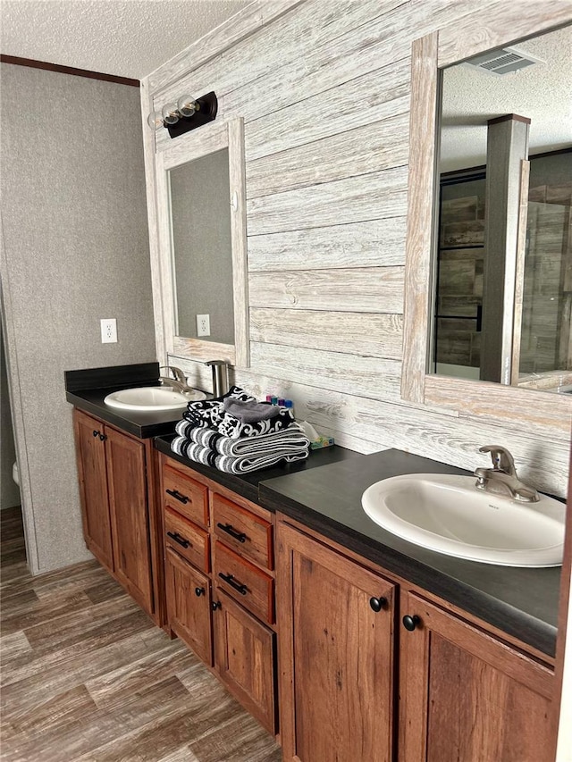 bathroom with a textured ceiling, crown molding, vanity, and wood-type flooring