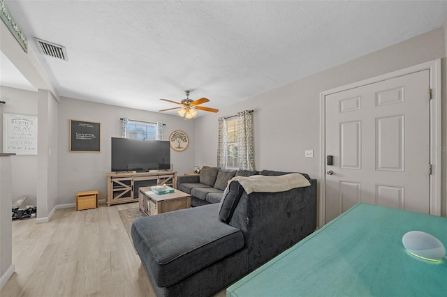 living room featuring ceiling fan, light hardwood / wood-style floors, and a textured ceiling