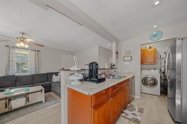 kitchen featuring washer / clothes dryer, stainless steel appliances, light wood-type flooring, ceiling fan, and sink