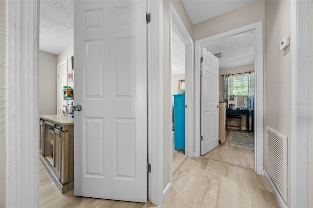 corridor featuring a textured ceiling and light hardwood / wood-style flooring