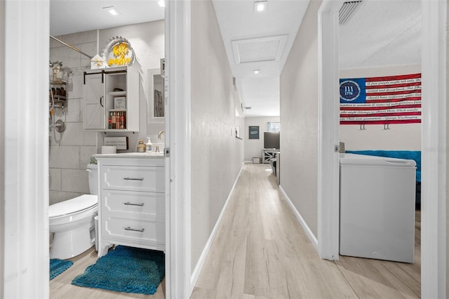 hall with washer / dryer and light hardwood / wood-style flooring