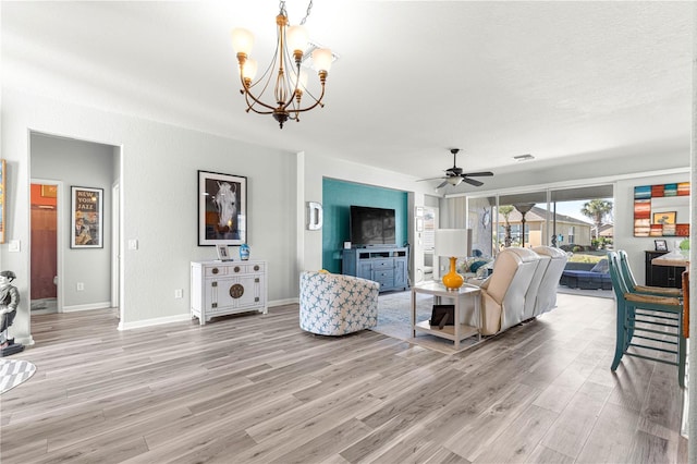 living room with ceiling fan with notable chandelier, a textured ceiling, and light hardwood / wood-style flooring