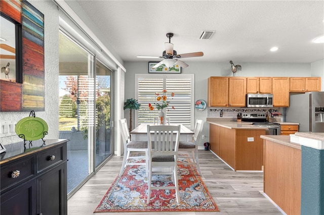 kitchen with a center island, tasteful backsplash, light hardwood / wood-style flooring, and appliances with stainless steel finishes