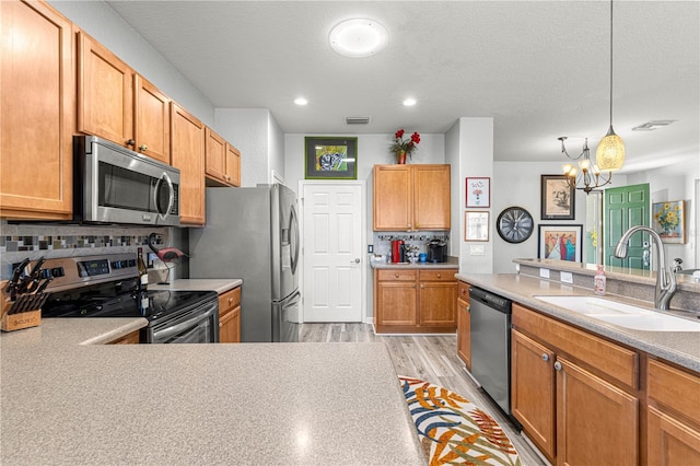 kitchen with stainless steel appliances, a notable chandelier, pendant lighting, sink, and tasteful backsplash