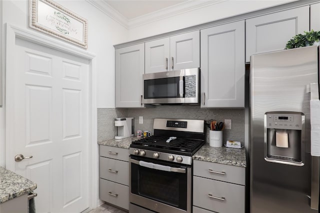 kitchen featuring gray cabinetry, light stone counters, crown molding, stainless steel appliances, and backsplash