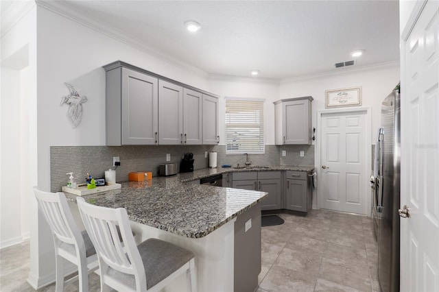 kitchen featuring a kitchen breakfast bar, dark stone countertops, gray cabinets, appliances with stainless steel finishes, and kitchen peninsula