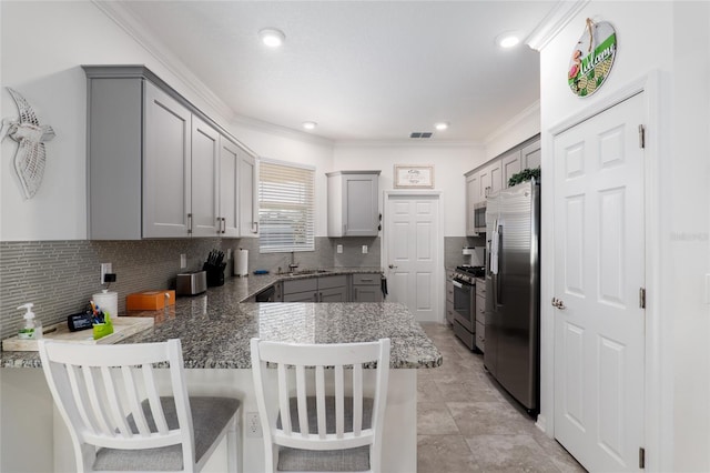 kitchen with kitchen peninsula, gray cabinets, a breakfast bar area, and stainless steel appliances