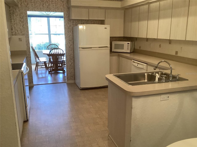 kitchen with sink, kitchen peninsula, and white appliances