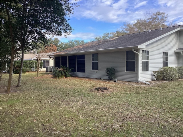 rear view of house with a yard and central AC