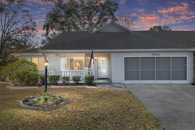 view of front facade featuring covered porch, a lawn, and a garage