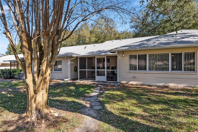 rear view of house with a yard and a sunroom