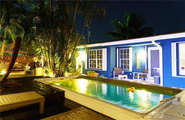 pool at night with a wooden deck