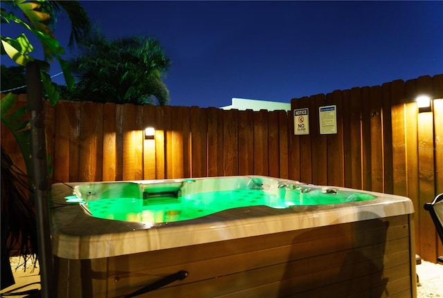 patio at night featuring a hot tub