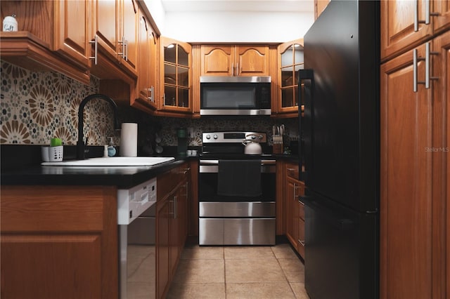 kitchen featuring decorative backsplash, sink, stainless steel appliances, and light tile patterned flooring