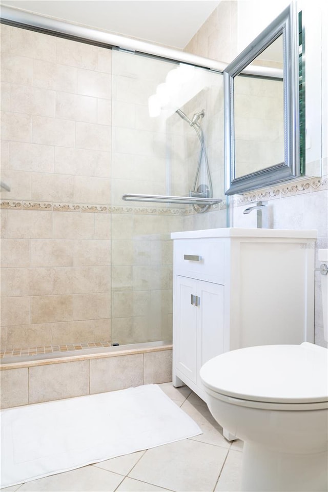 bathroom with an enclosed shower, vanity, toilet, and tile patterned flooring