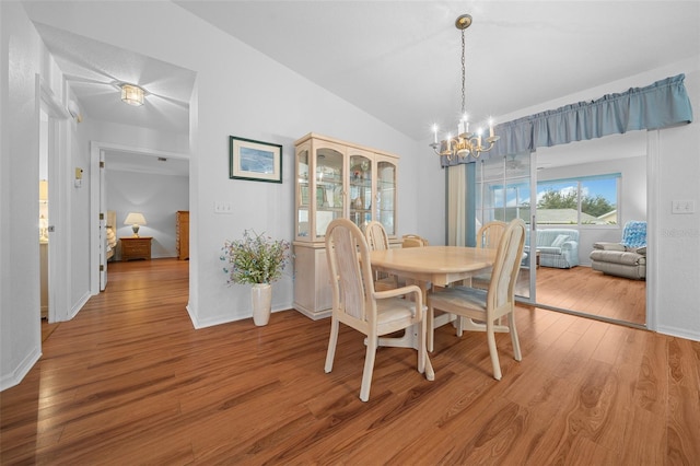 dining space with vaulted ceiling, a chandelier, and hardwood / wood-style flooring