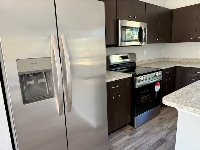 kitchen featuring light wood-type flooring, appliances with stainless steel finishes, and dark brown cabinets