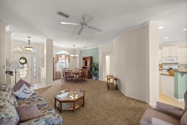 carpeted living room with ornamental molding and ceiling fan with notable chandelier