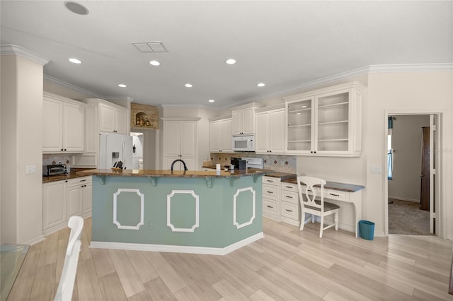 kitchen featuring white appliances, white cabinetry, and a kitchen island with sink