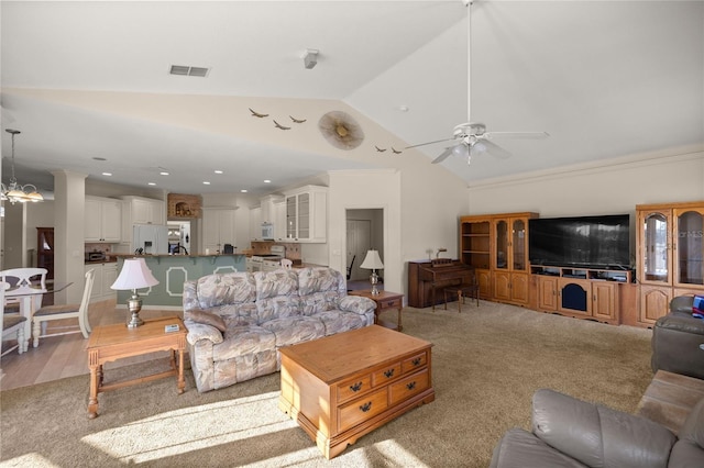 living room with ceiling fan with notable chandelier, lofted ceiling, crown molding, and light colored carpet