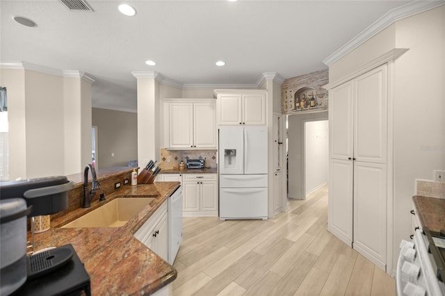 kitchen featuring sink, white appliances, white cabinetry, and dark stone countertops