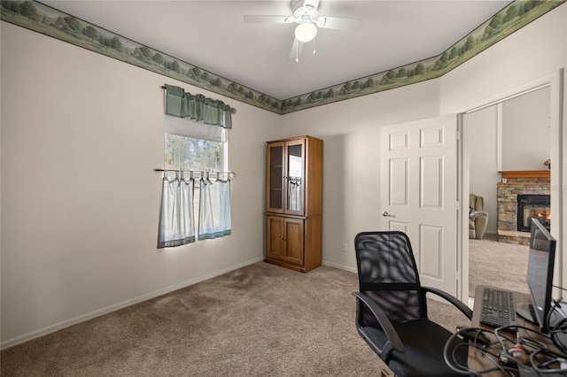 office space with ceiling fan, carpet flooring, and a stone fireplace