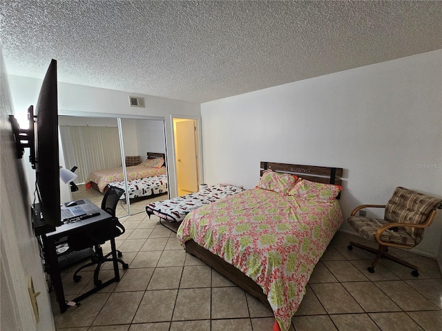 tiled bedroom with a textured ceiling and a closet