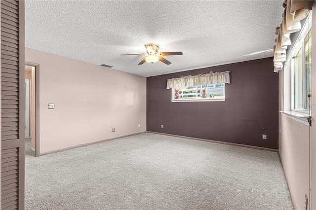 spare room featuring a textured ceiling, ceiling fan, and carpet