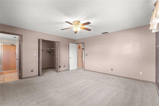 unfurnished bedroom featuring ceiling fan, a textured ceiling, a closet, and light carpet