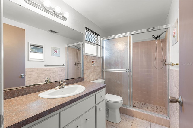 bathroom featuring toilet, vanity, tile patterned floors, and walk in shower